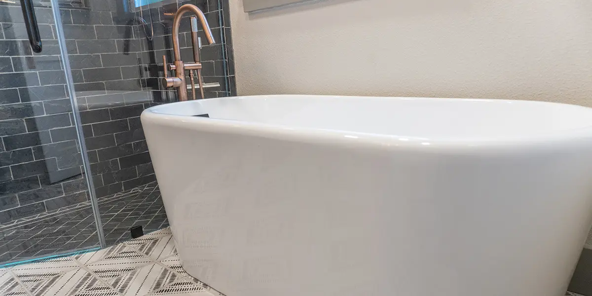 Elegant bathroom remodel with dark shower tile, mosaic floor tile, and freestanding tub