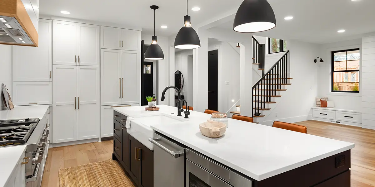 New modern kitchen renovation with large black island and white tall cabinets