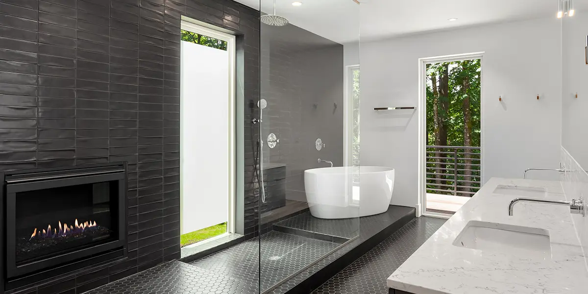 Modern bathroom renovation with black shiny subway tile and freestanding tub