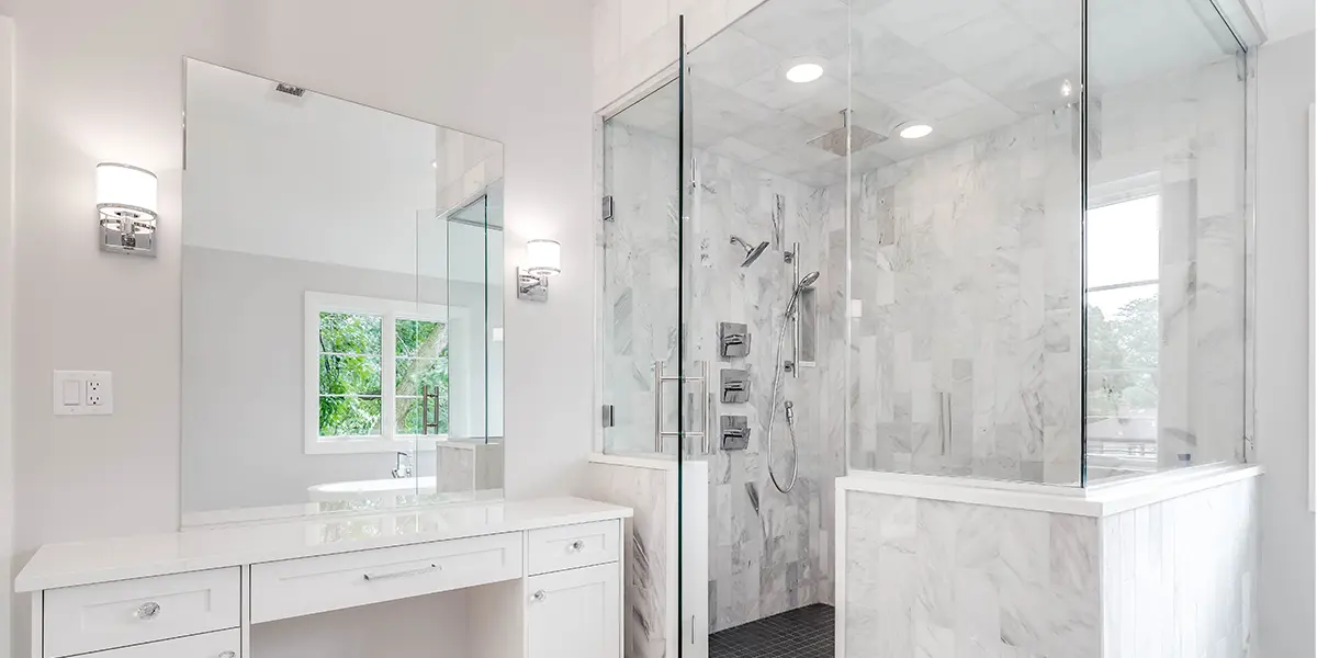 Bathroom with white shower walls, glass shower doors, and white vanity with large window