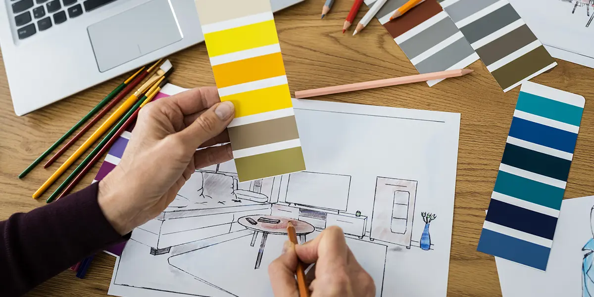 View of woman hands sketching a living room design while holding color swatches