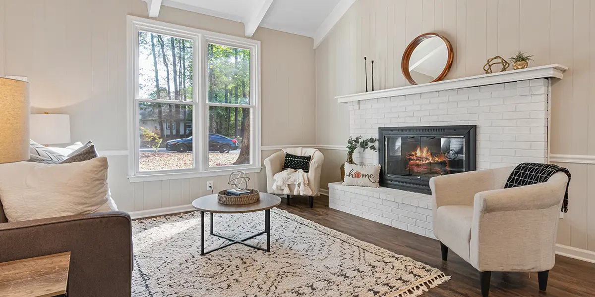 Renovated living room with large white fireplace and rustic rug with comfortable chairs
