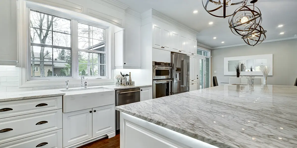 Large open space kitchen with white kitchen island and farmhouse sink with overhead lights