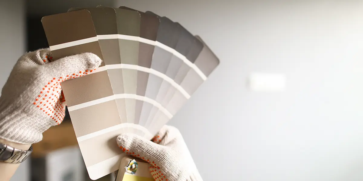 Close-up of person choosing paint colors from swatches for kitchen remodeling