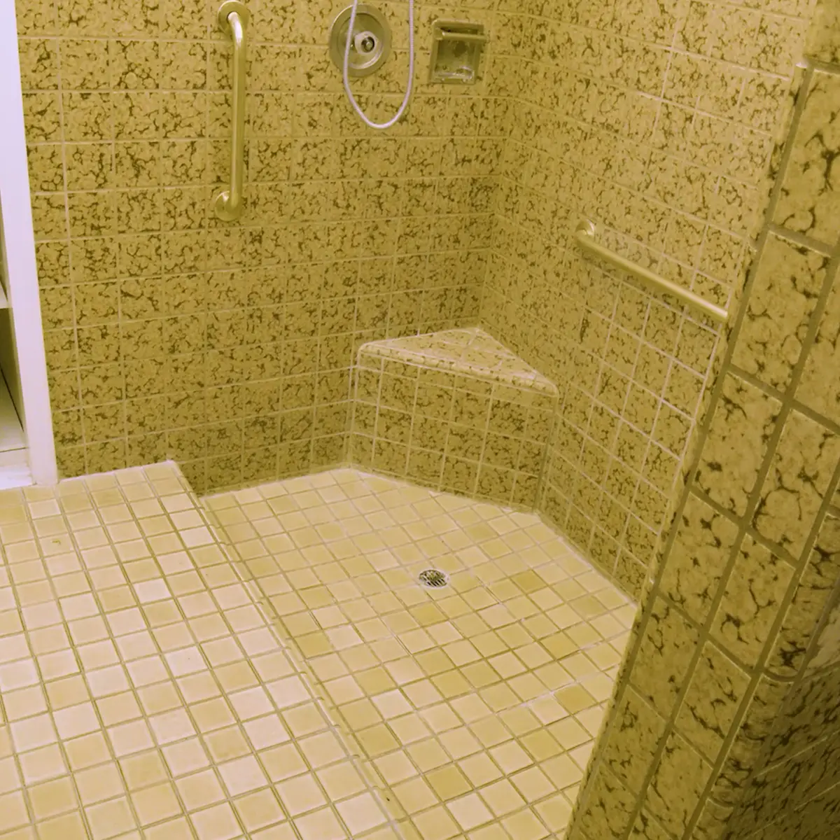A shower with small floor and walls tiling before remodel