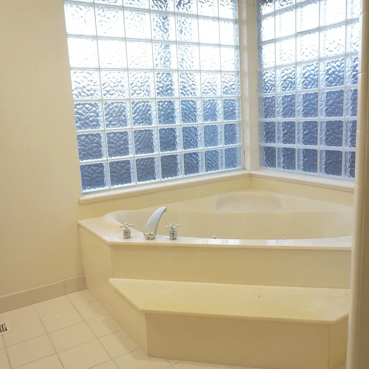 A jacuzzi tub with old an old window in a bathroom before its remodel