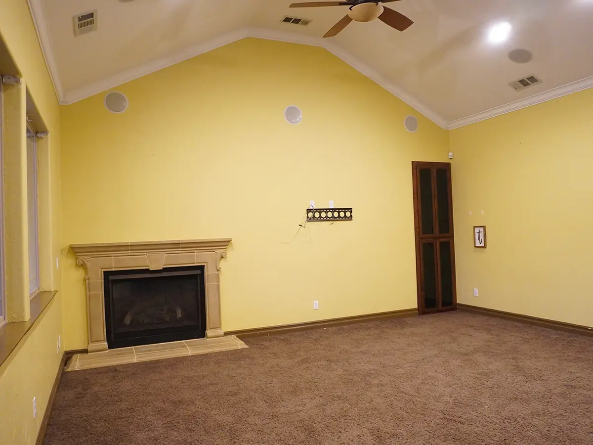 Am empty room painted in yellow and a fireplace