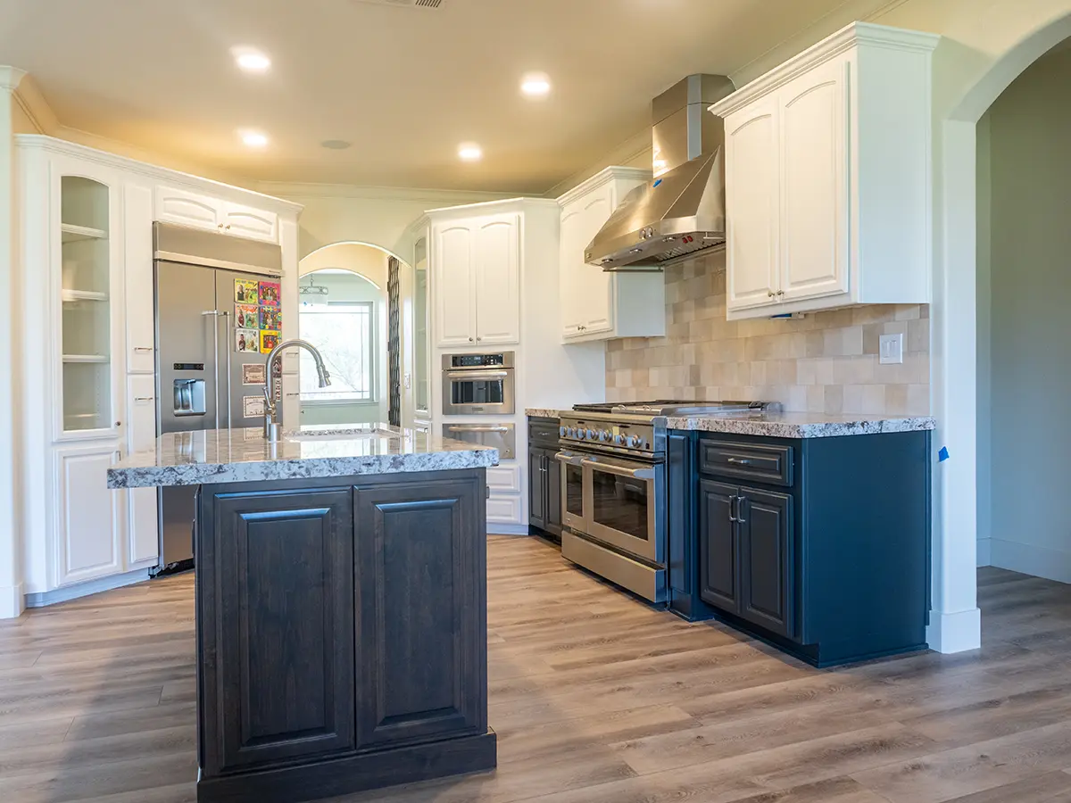 A dark kitchen island with dark base cabinets and white upper cabinets