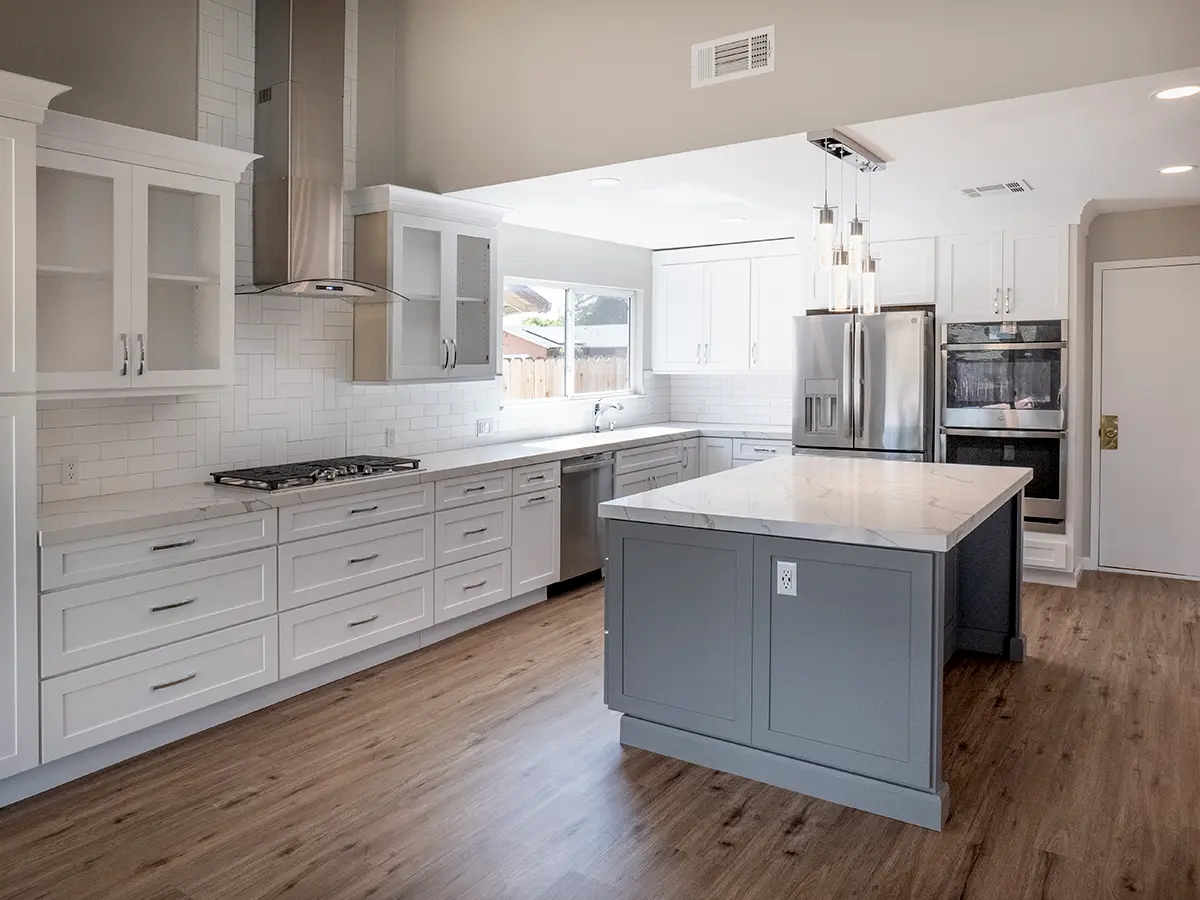 LVP flooring in a kitchen with white cabinets and a kitchen island with marble counter