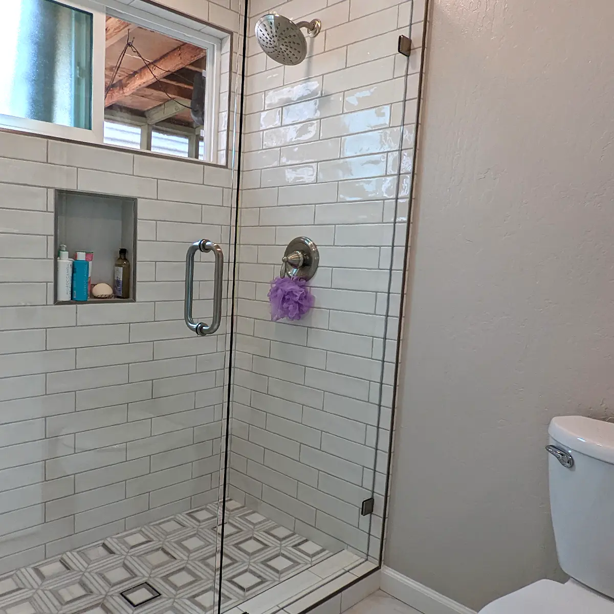 Glass shower with rectangular tile and a purple sponge