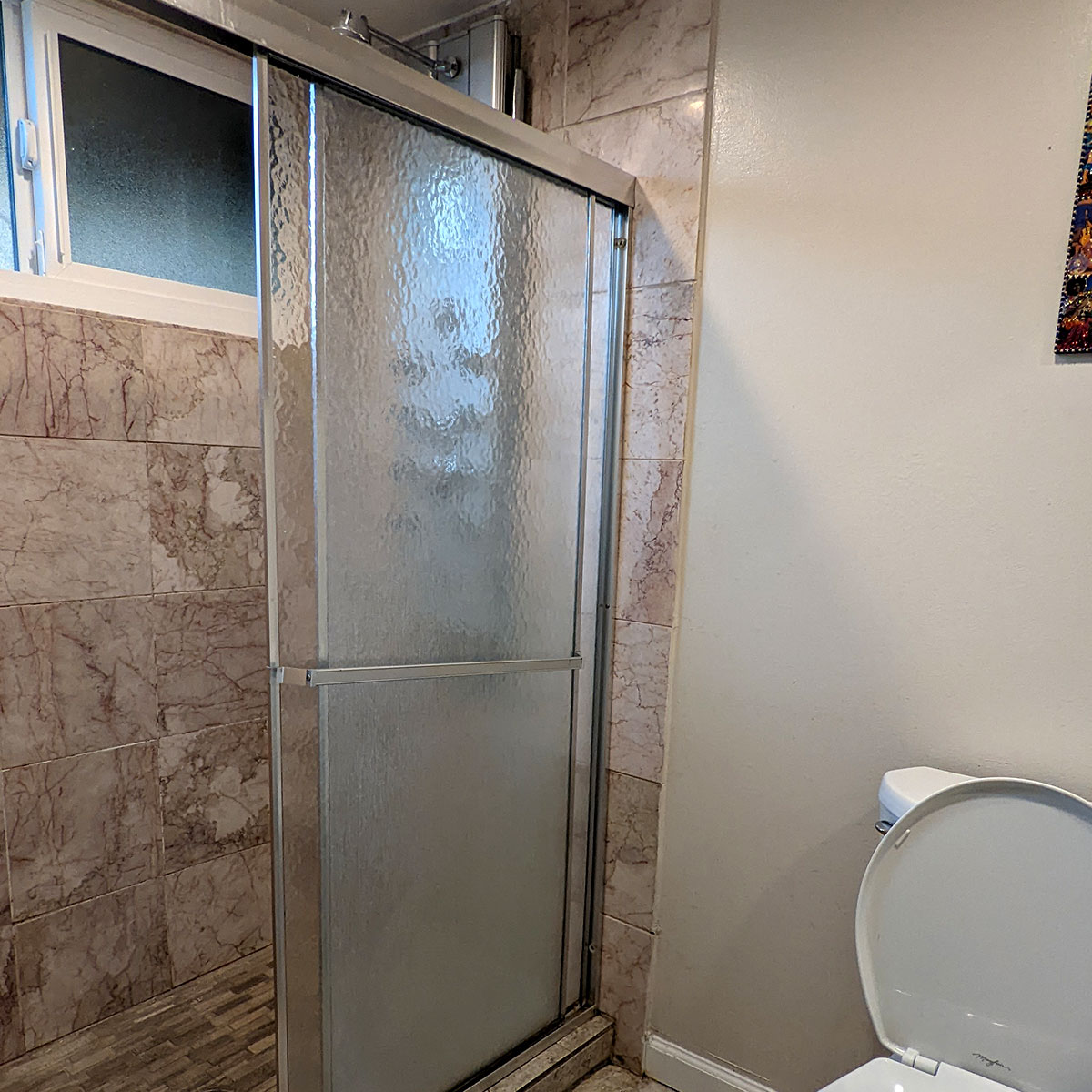 A shower with a glass sliding door before its remodel