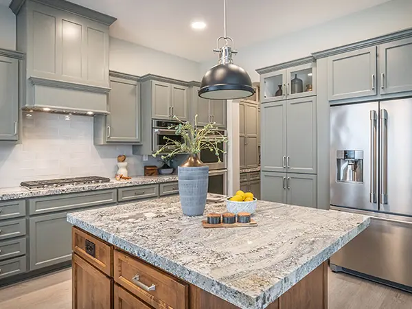 A granite countertop with wood cabinets in a kitchen with light gray cabinets