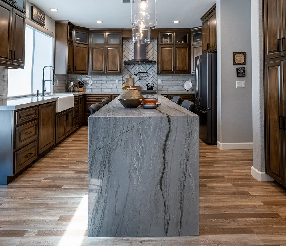 A kitchen with LVP flooring, wood cabinets, and a quartz island