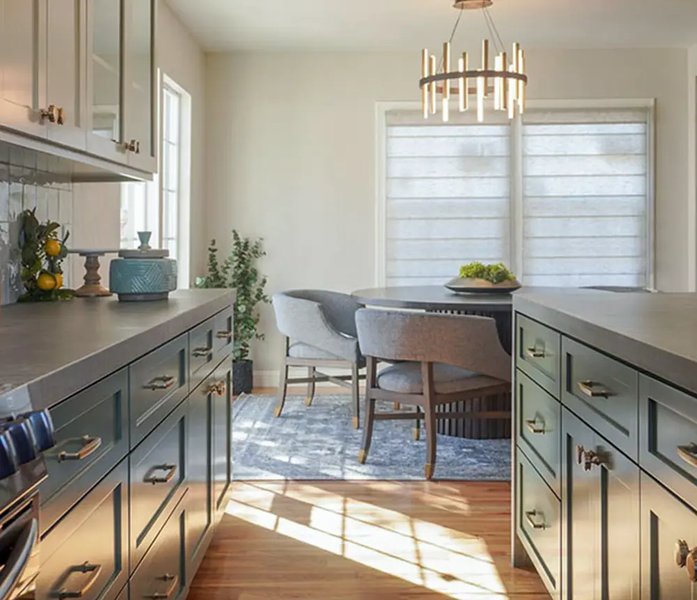 Green cabinets with concrete countertops and a dining table