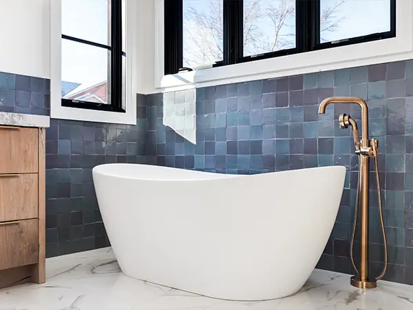 A bathtub with blue tile backsplash and a golden faucet