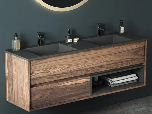 A beautiful wooden vanity with dark countertop and faucets