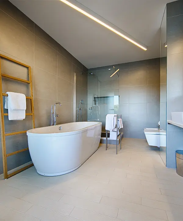 A free standing tub in a modern bathroom with large tile flooring