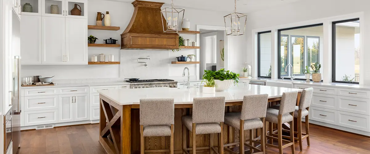 A huge kitchen island with chairs and white cabinets