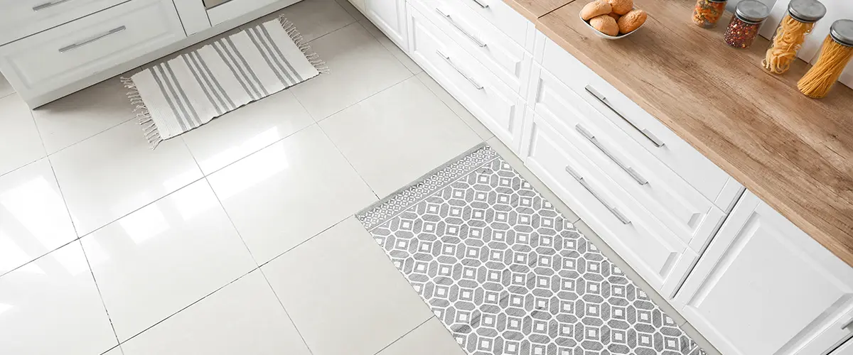 A large tile kitchen floor with two mats