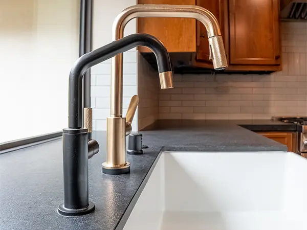 A black and golden faucet on an undermount sink