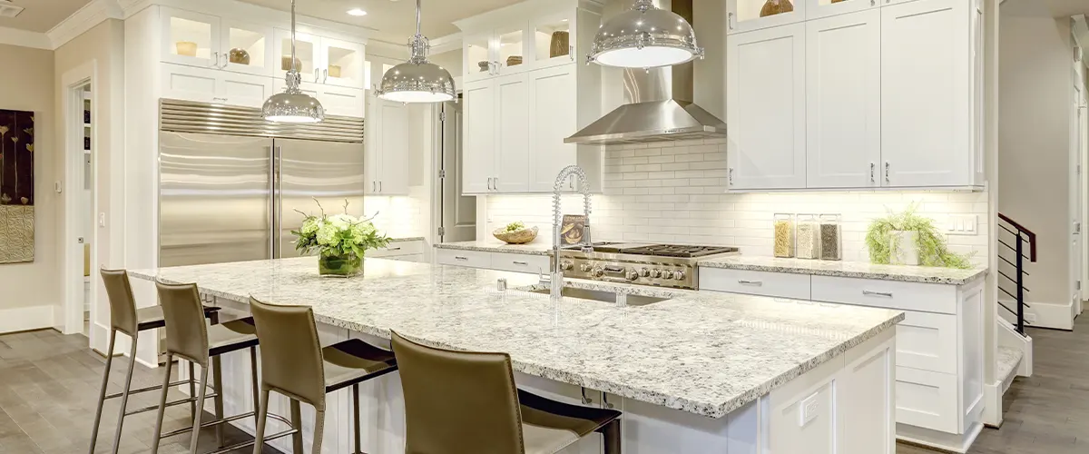 large kitchen wtih white cabinets and marble island