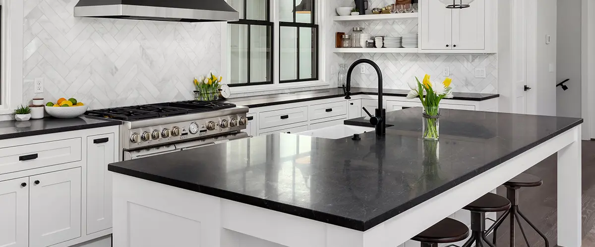 Black kitchen countertop with white cabinets and open space large island