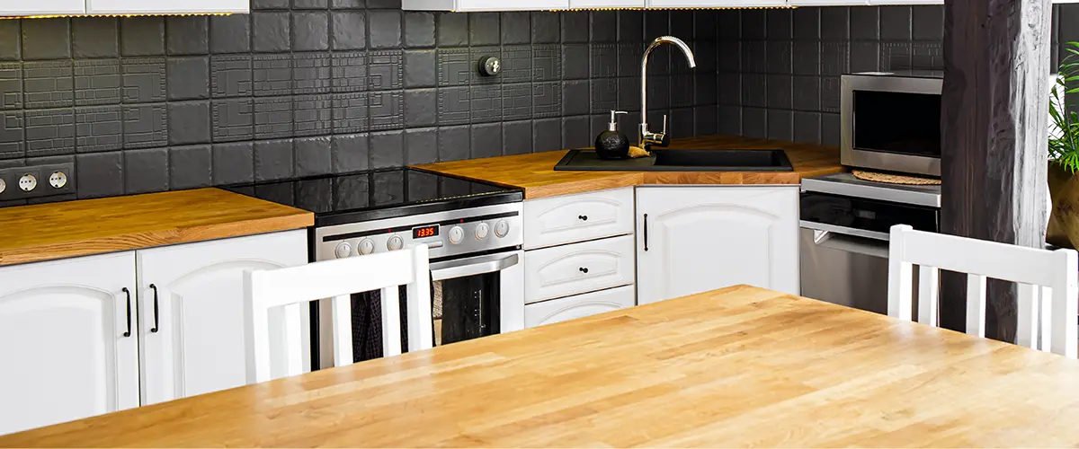 White kitchen with butcher block countertop and black backsplash