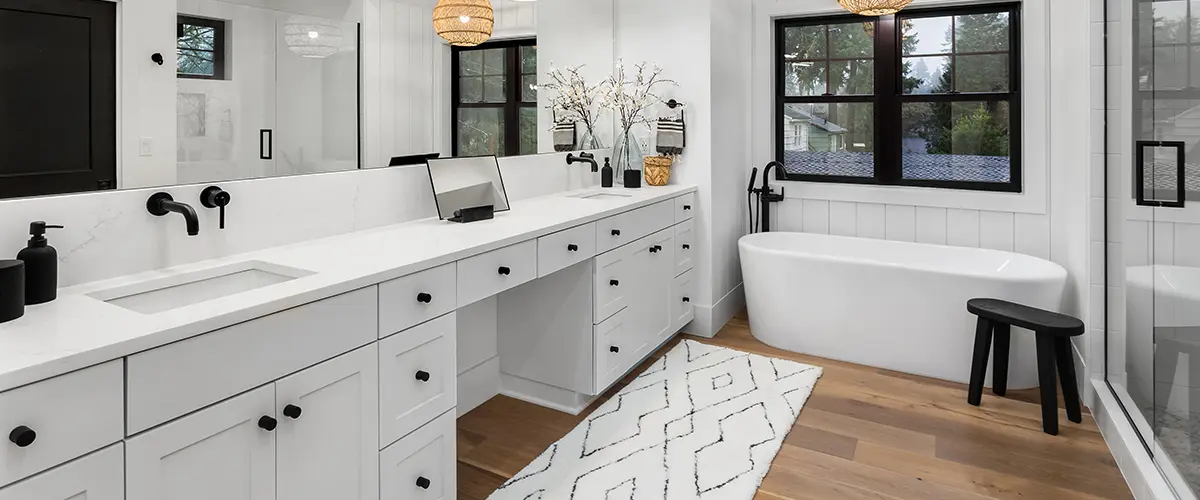 bathroom addition with white vanities and black fixtures and hardware