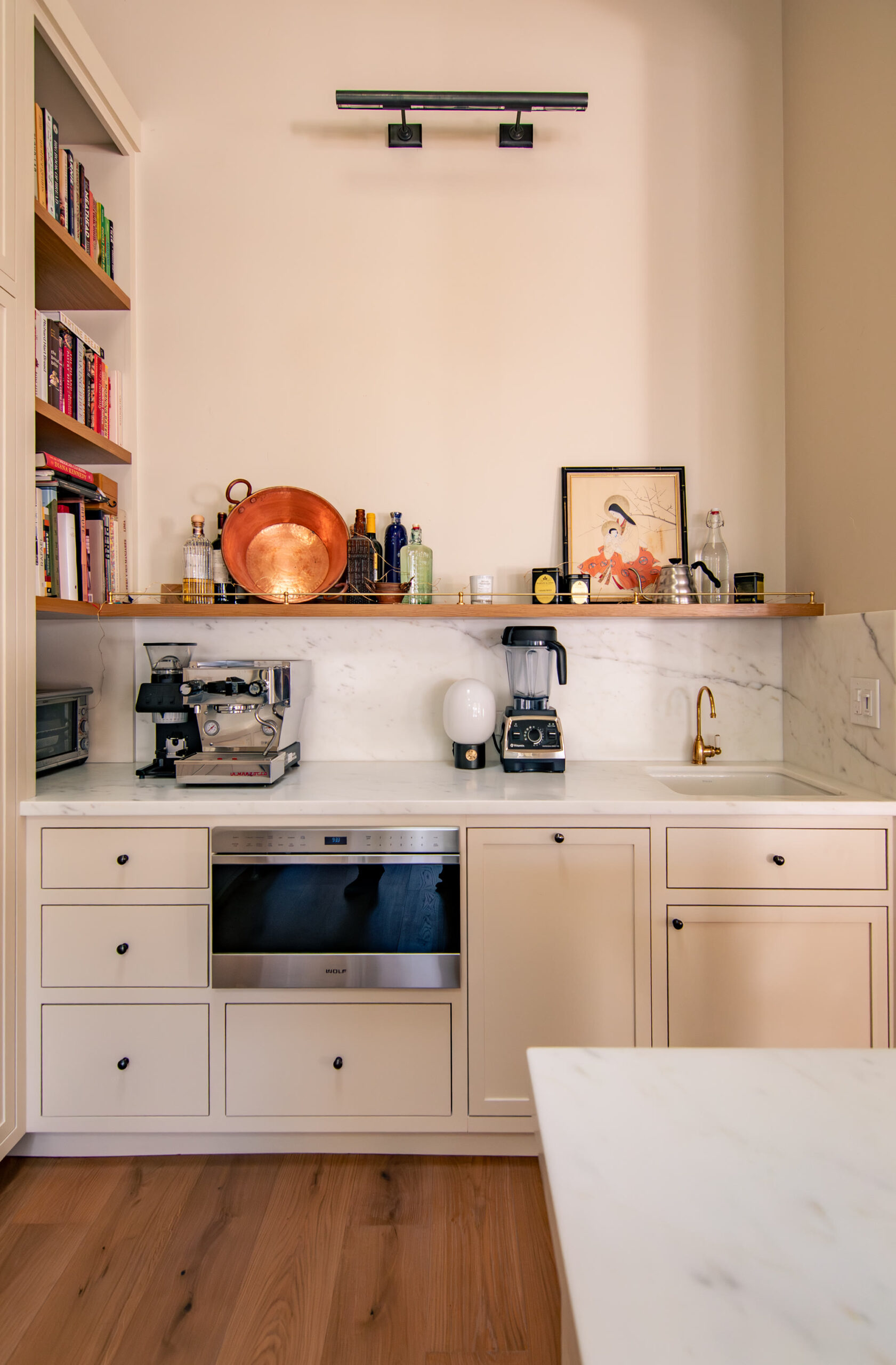 Coffee bar with brass faucet, marble backsplash, and a floating white oak shelf