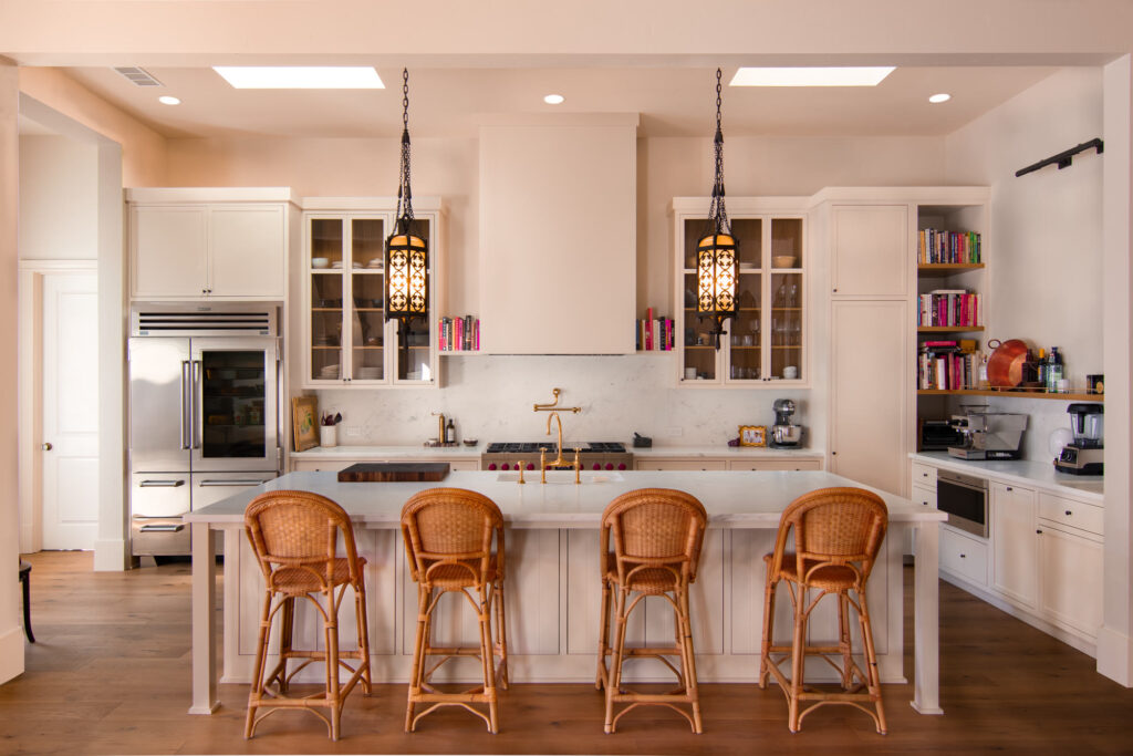 Custom luxury kitchen with a Carrara marble island, rattan stools, and iron lantern pendants